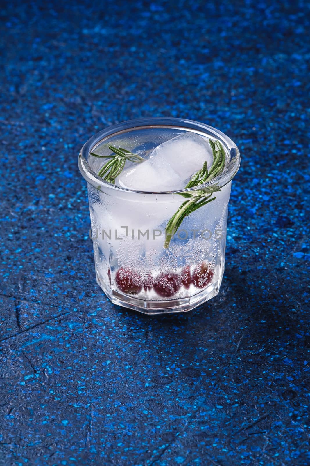 Fresh ice cold carbonated water drink in glass on blue textured background, angle view
