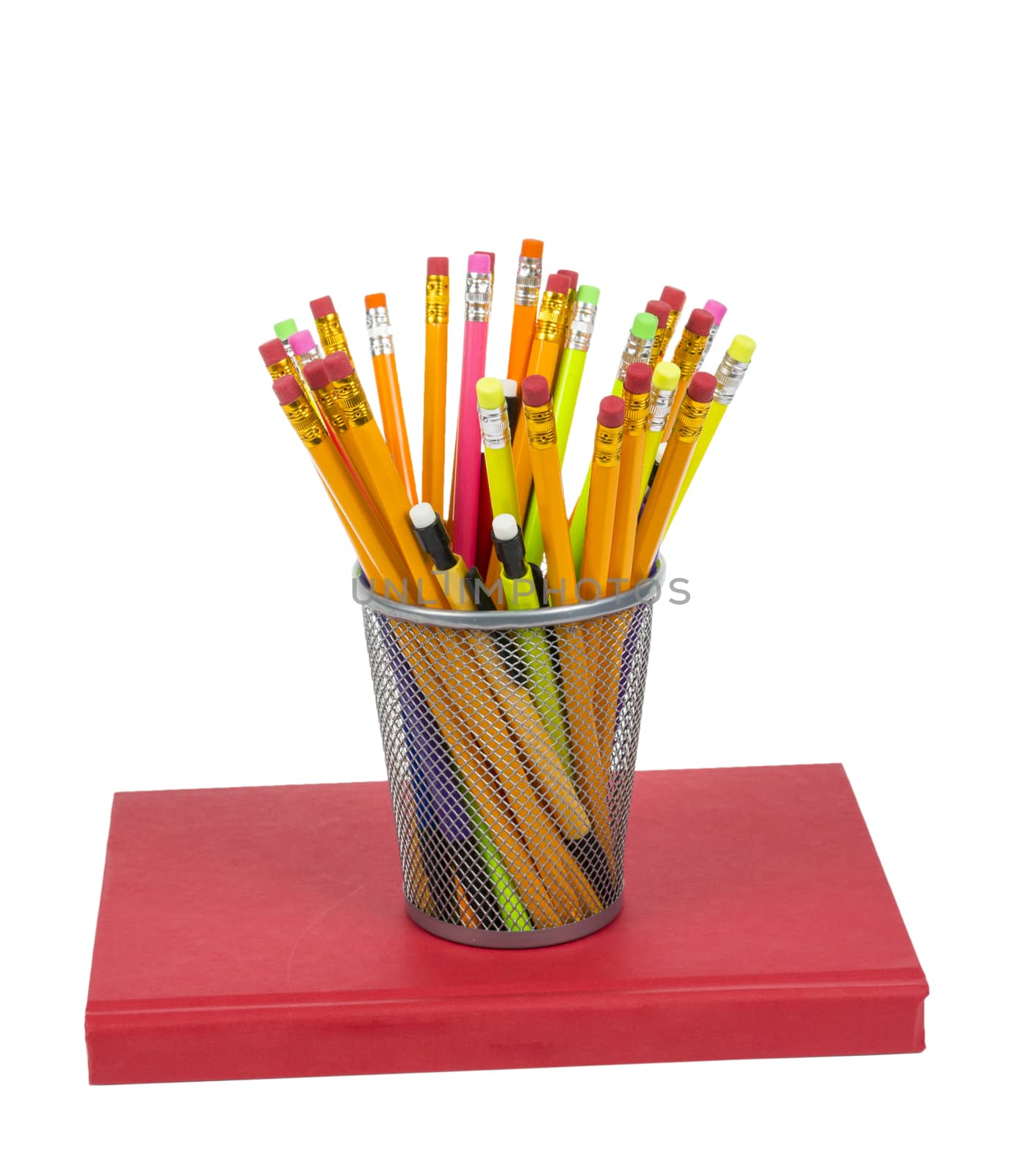 Isolated on white shot of a bunch of colorful pencils in a holder resting on a red book.