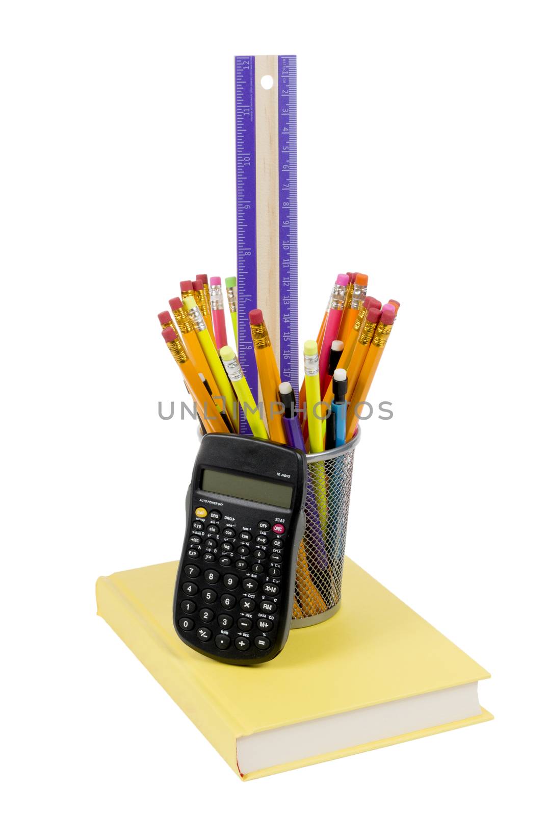 Vertical photograph of brightly colored pencils  and calculator on a yellow book. Isolated on white background.