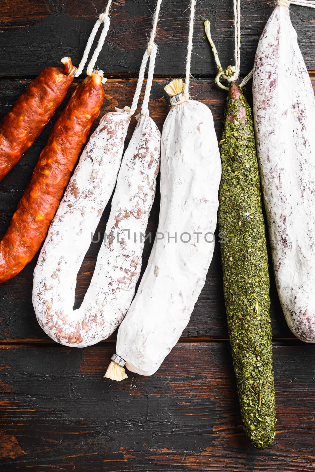 Dry cured spanish meat sausages hanging on old wooden table, topview.