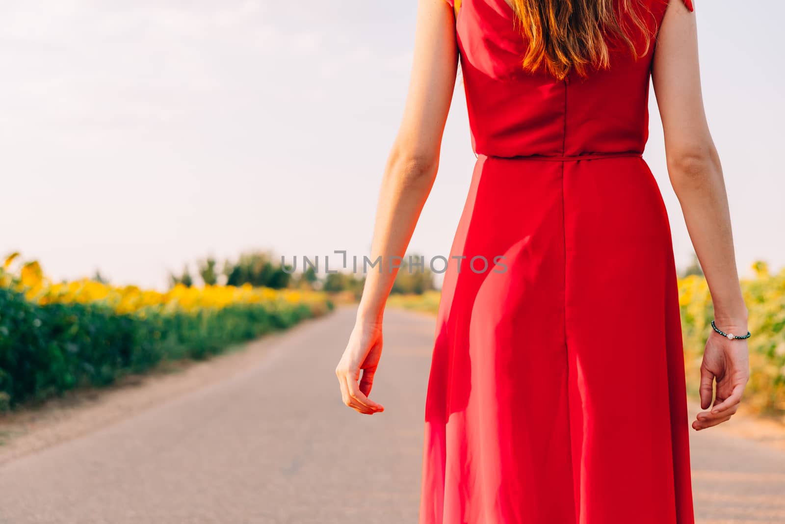 woman with red dress backwards in road with sunflowers by Fotoeventis