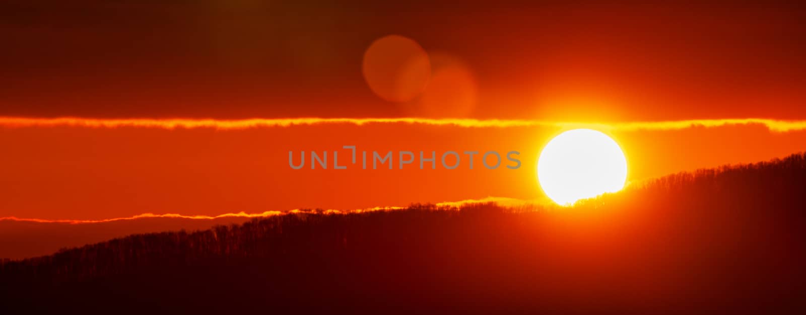 Amazing sunrise in mountains, sunny disk rises from tops of hill. Natural lens flare in sky, sunbeam light leaks. Early morning weather, nature and environment panoramic landscape.