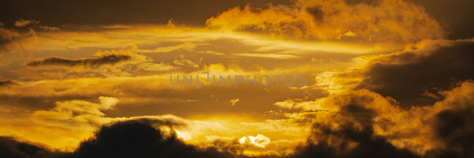 Panoramic view of dramatic clouds illuminated rising of sun floating in sky to change weather. Soft focus, motion blur sky majestic meteorology cloudscape.
