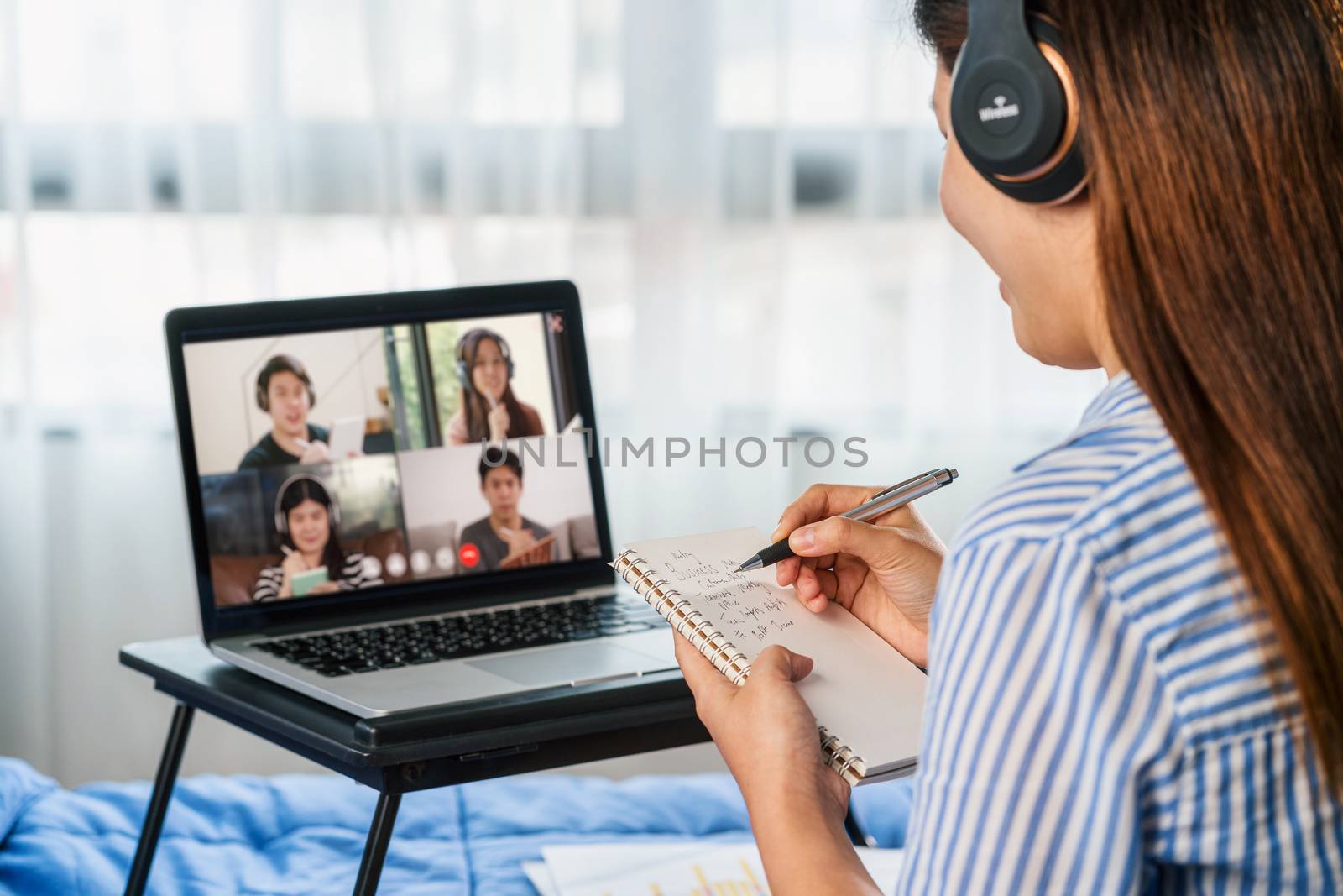 Rear view of Asian woman working and online meeting via video co by Tzido