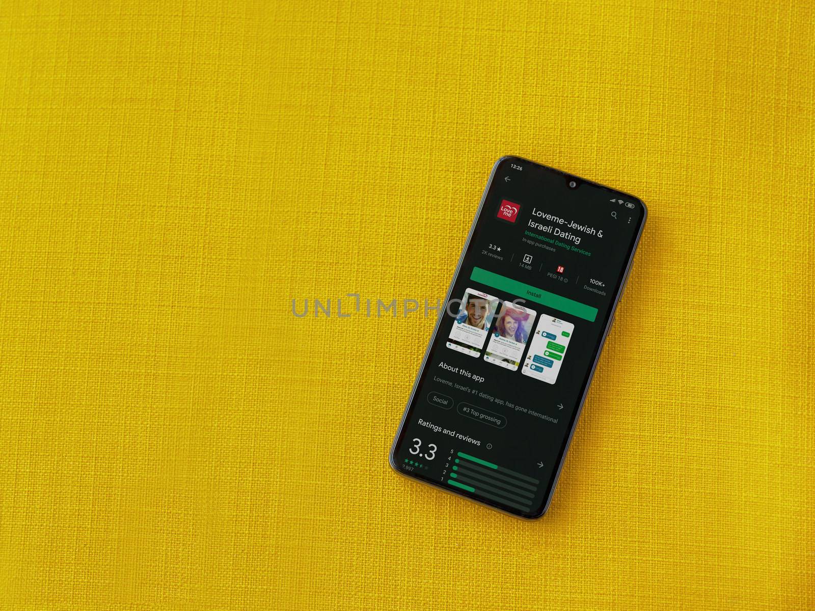 Lod, Israel - July 8, 2020: Loveme app play store page on the display of a black mobile smartphone on a yellow fabric background. Top view flat lay with copy space.