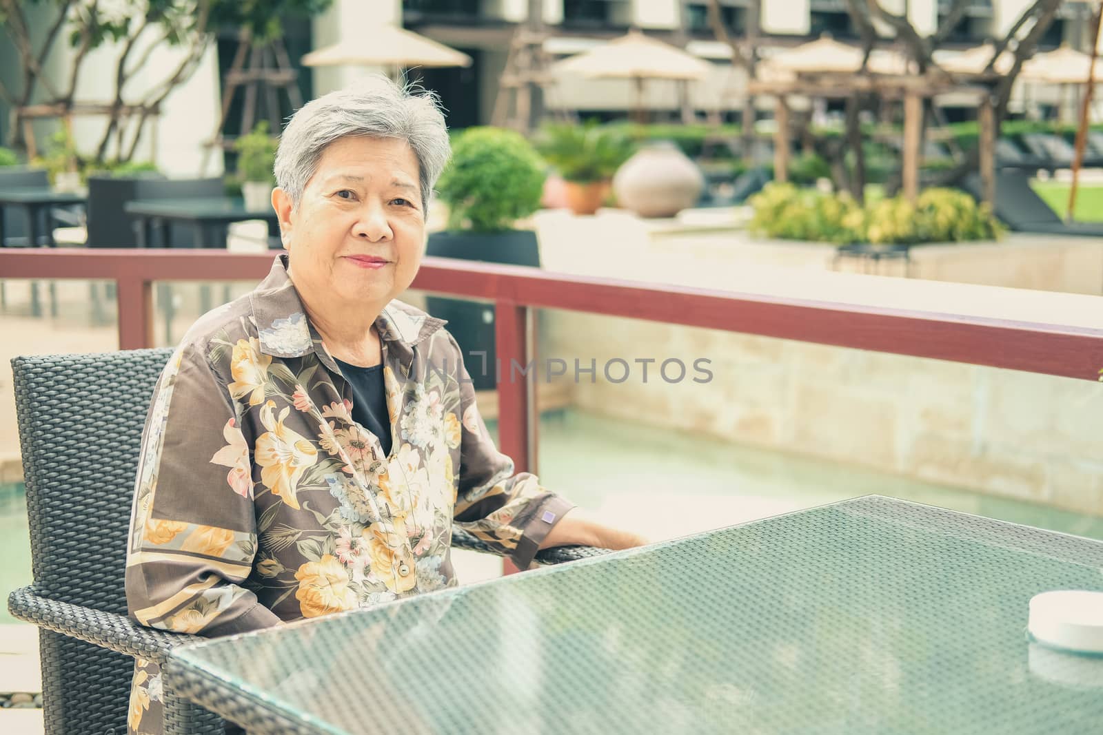 asian elder female woman resting relaxing on balcony terrace at hotel resort. elderly senior leisure lifestyle