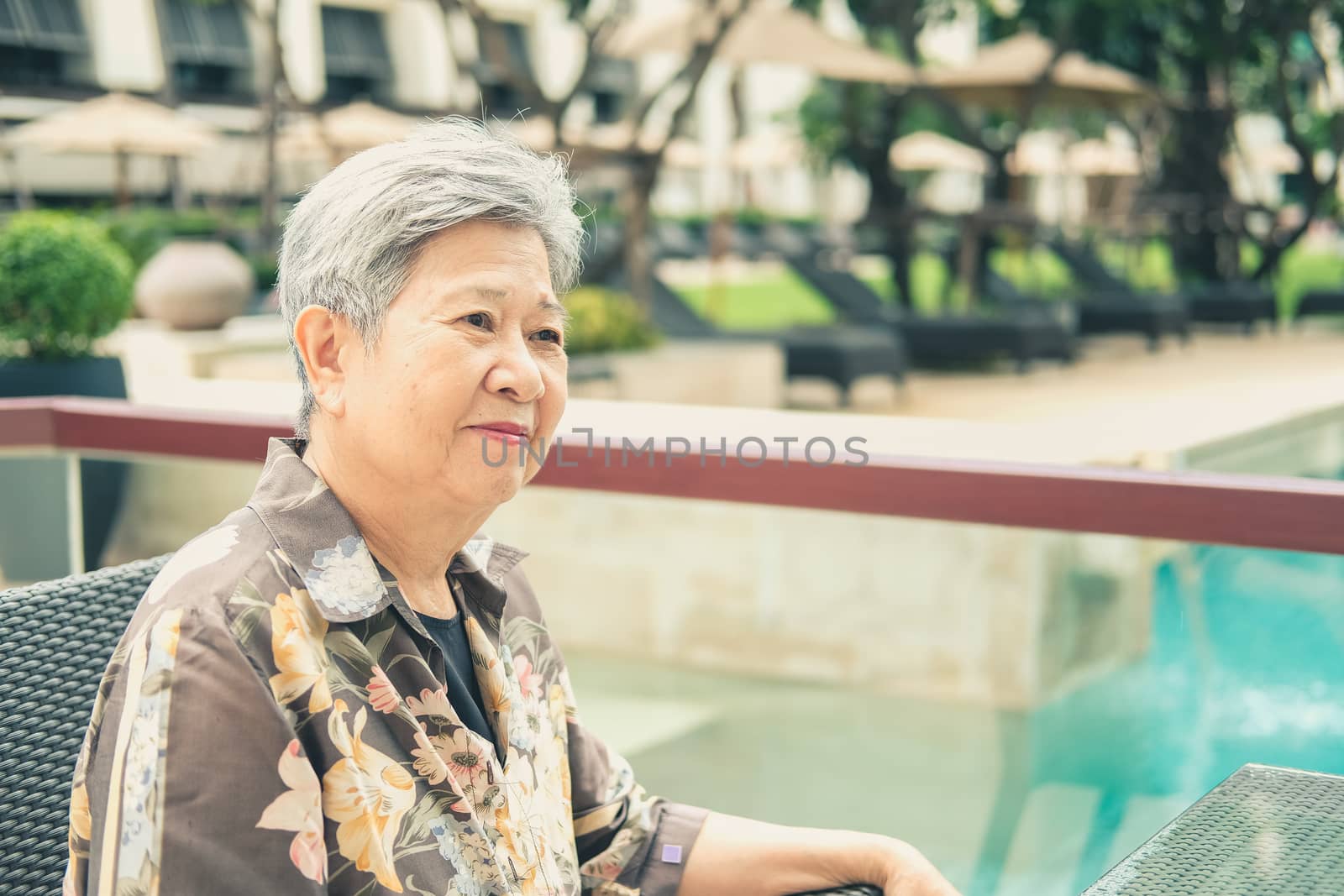 asian elder female woman resting relaxing on balcony terrace at hotel resort. elderly senior leisure lifestyle