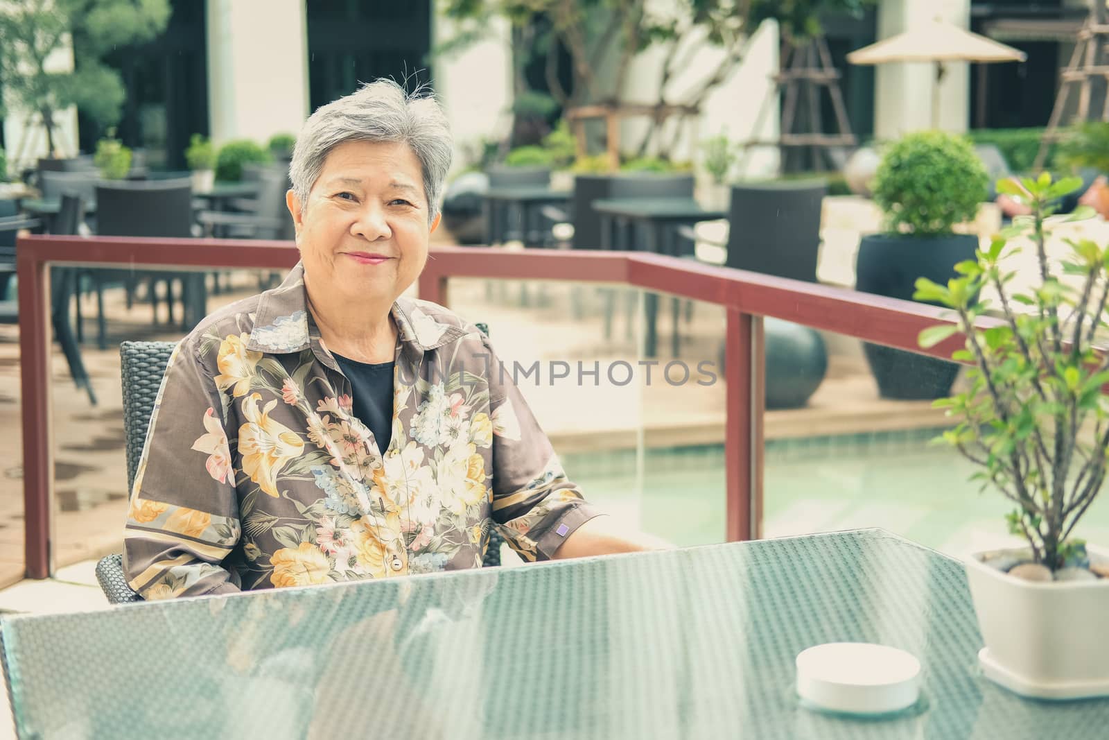 asian elder female woman resting relaxing on balcony terrace at hotel resort. elderly senior leisure lifestyle