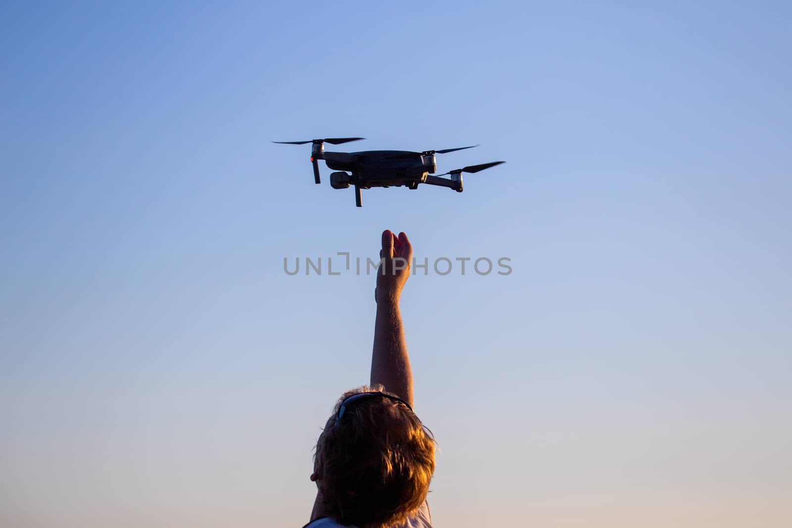 blonde caucasian man catching small quadcopter drone.