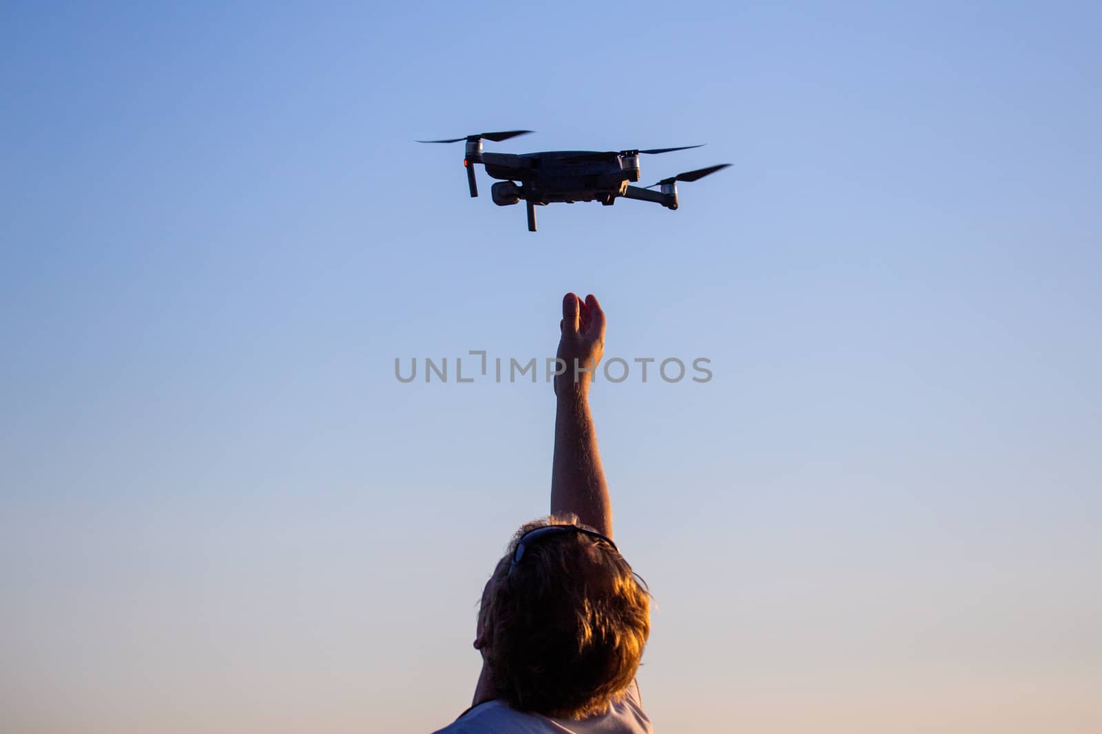 blonde caucasian man catching small quadcopter drone.