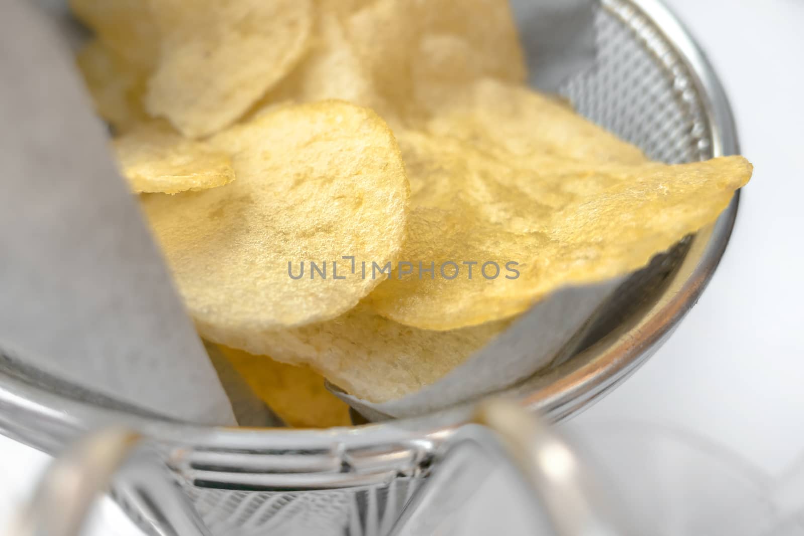 Potato chips in a bowl. Snack food. Fast food. Extreme close-up with selective focus. Defocused blurry background.