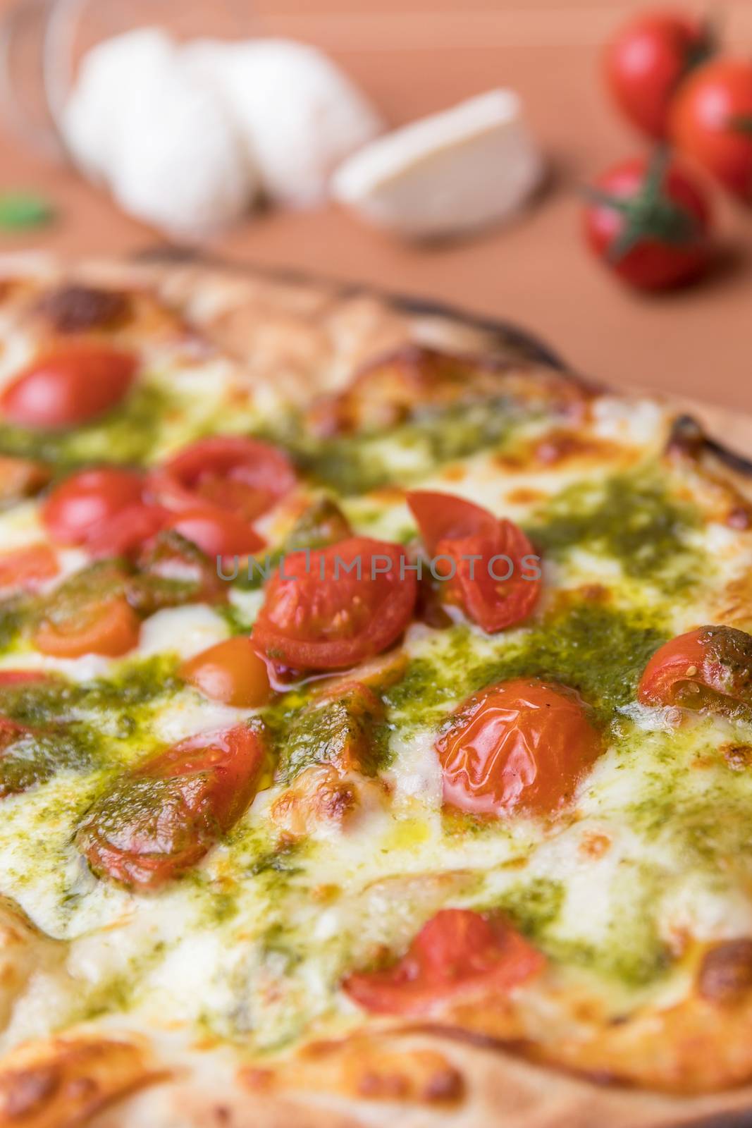 Italian pizza with cherry tomatoes, pesto sauce basil and mozzarella cheese baked in a wood oven. Italian cuisine.