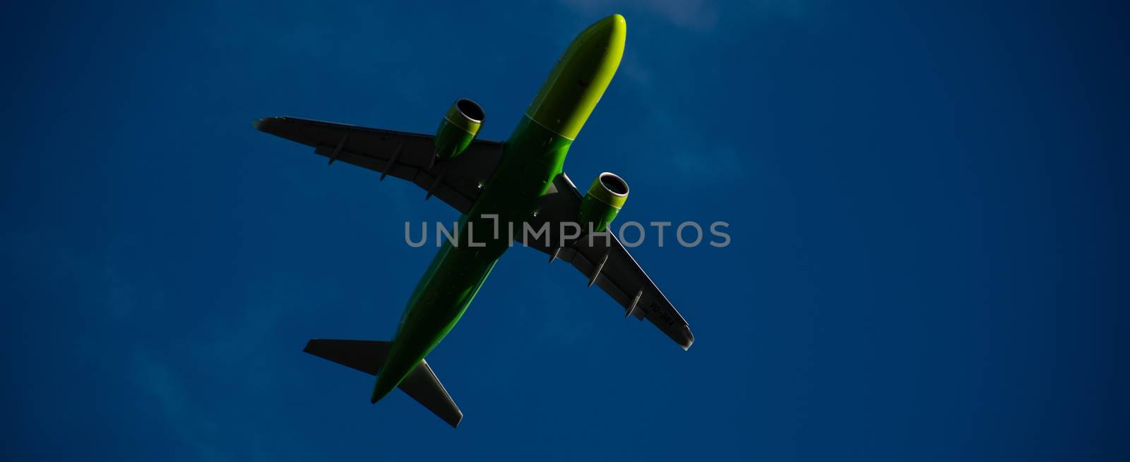 Silhouette of a green plane taking off against a blue sky