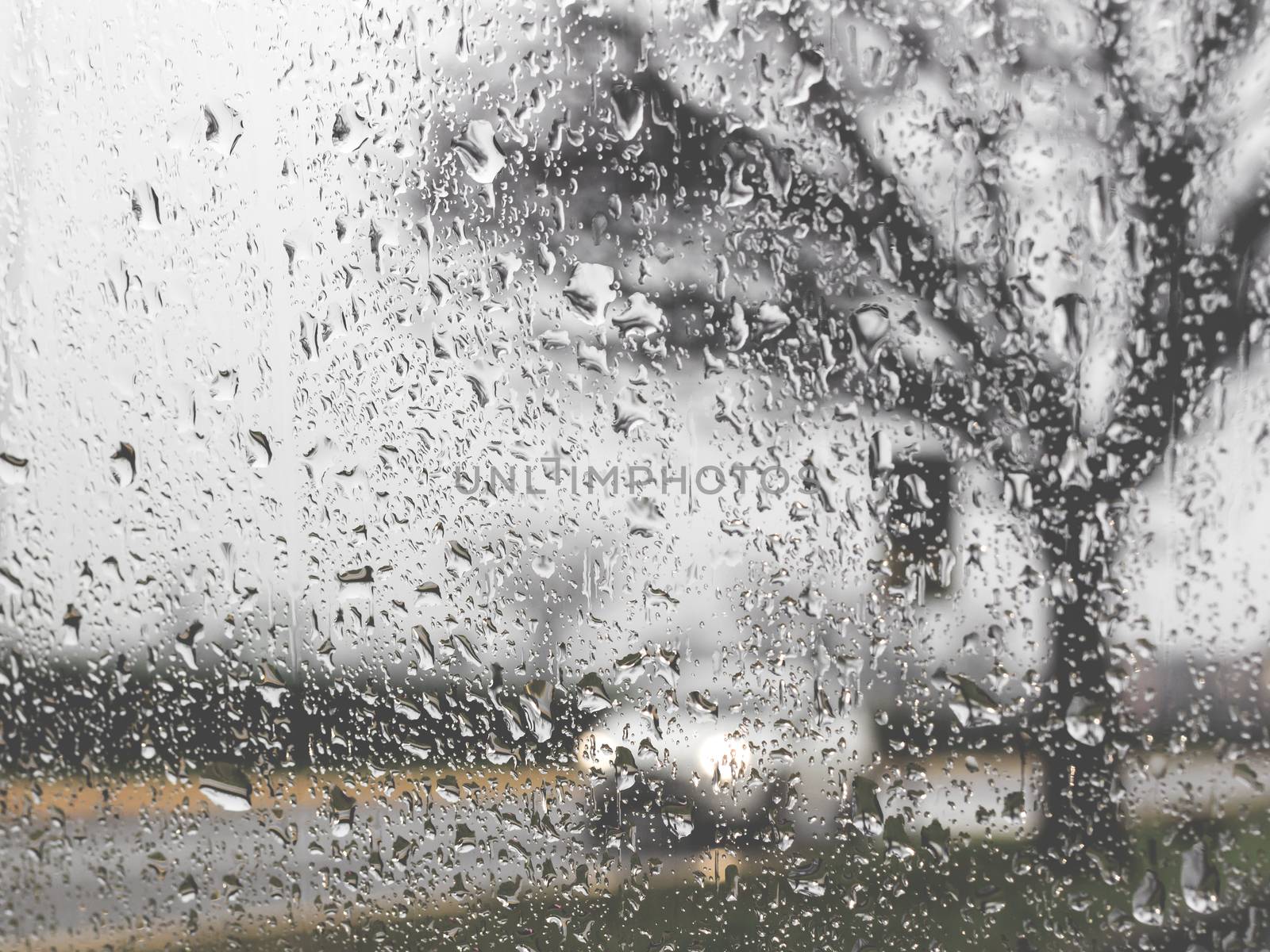 Rainy bad weather on the street. Raining and wet weather driving conditions on the road, traffic blurred, raindrops on car windscreen.