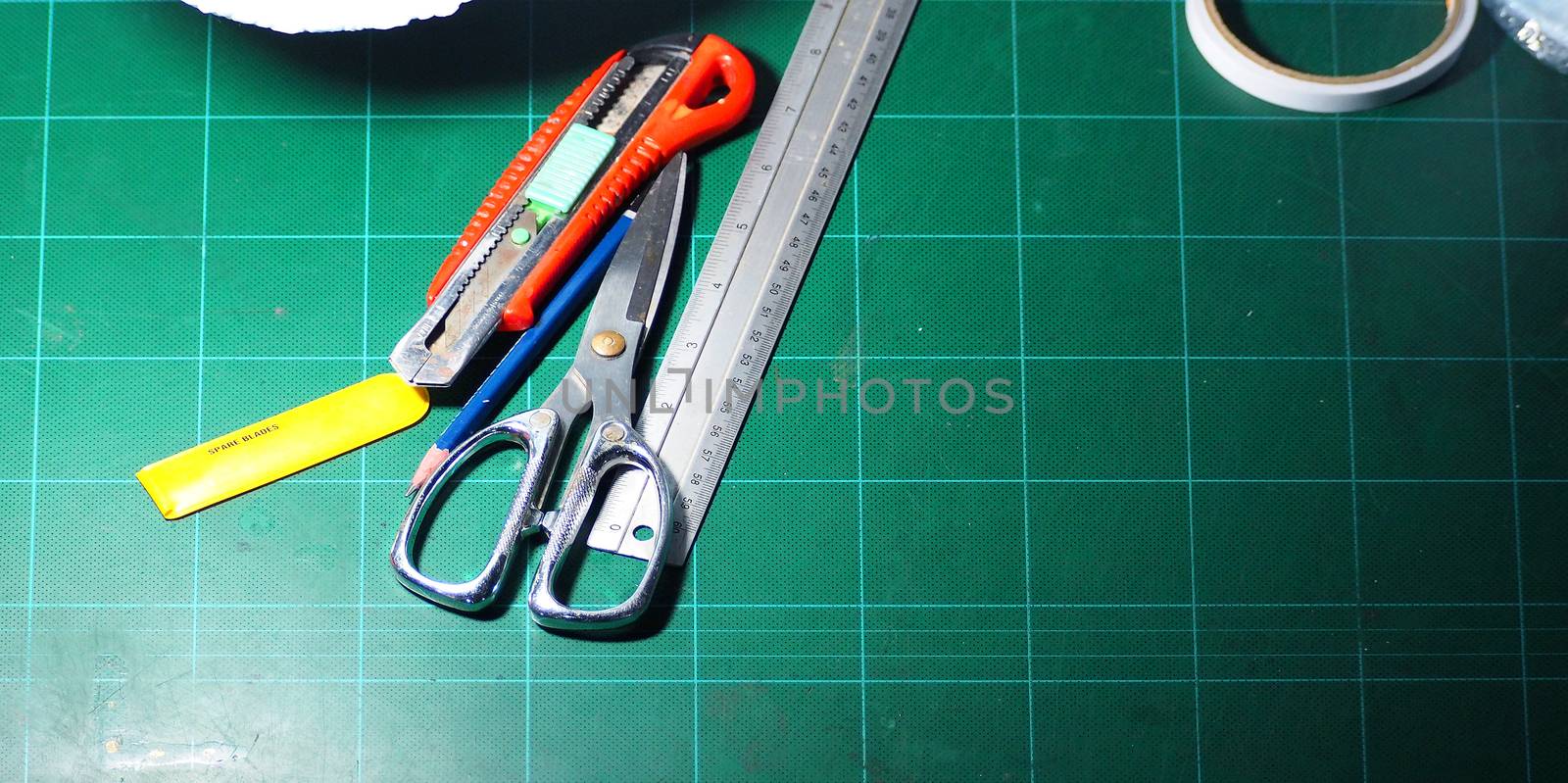 Scissor and cutter and ruler and pencil and blades on the green cutting mat and top view angle camera.