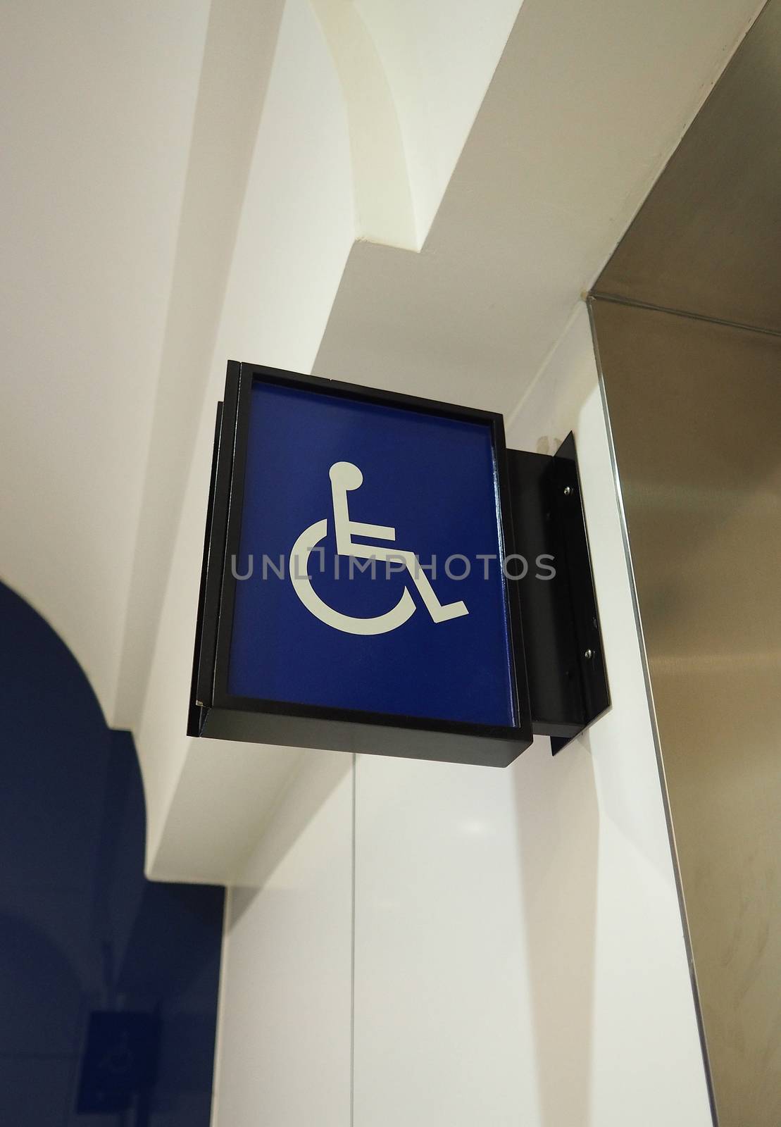 Real toilet sign or restroom direction tab and hanging on the wall and blue color and white icon.