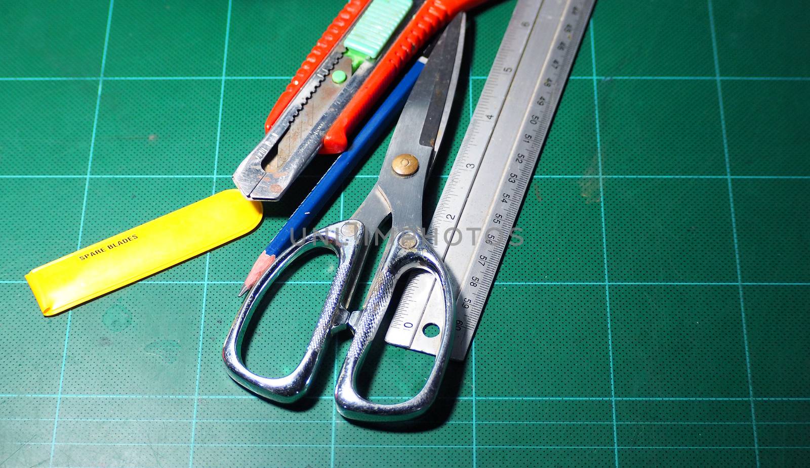 Scissor and cutter and ruler and pencil and blades on the green cutting mat and top view angle camera.