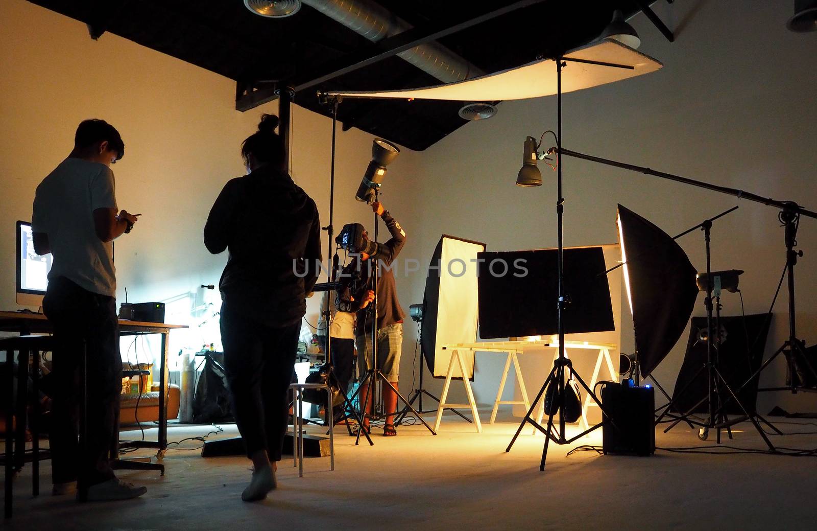 Silhouette of people working in production studio for shooting or recording by digital camera and lighting set.