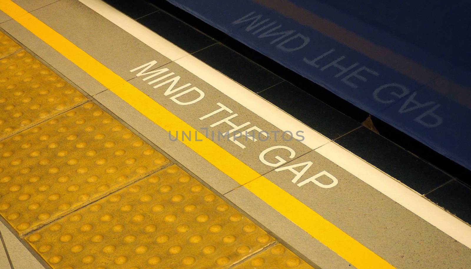 Mind the gap text sign on floor between train and platform station and high angle view.