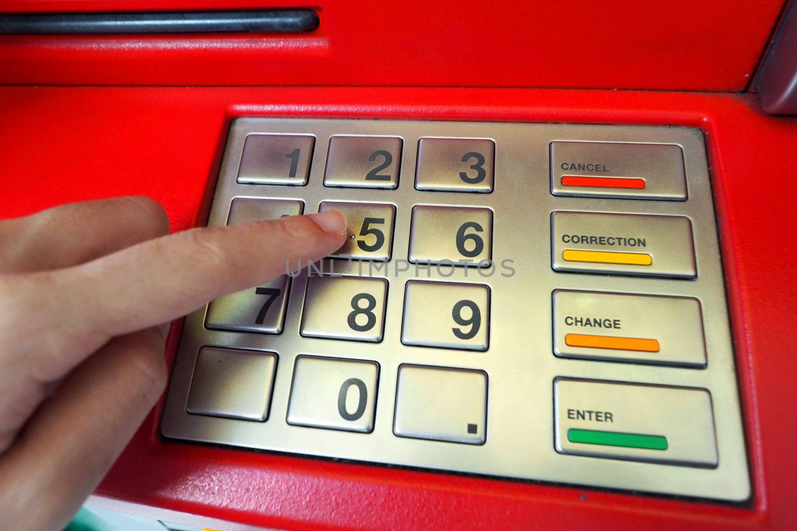 ATM machine red color and finger hand touch on number button for withdrawal and close-up shot.