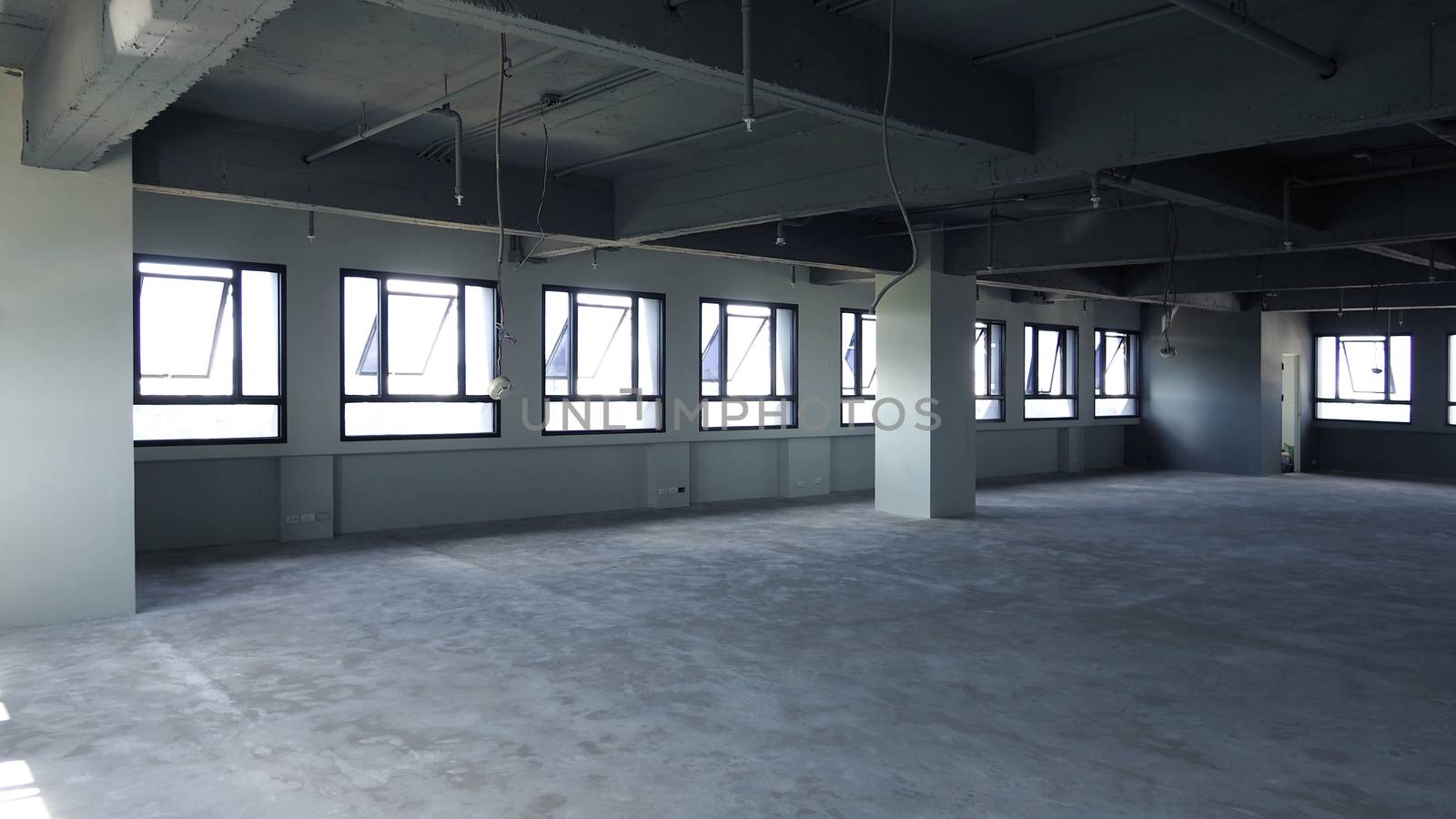 Abandoned office room that old and dirty floor and wall and have window around and indoor shot.