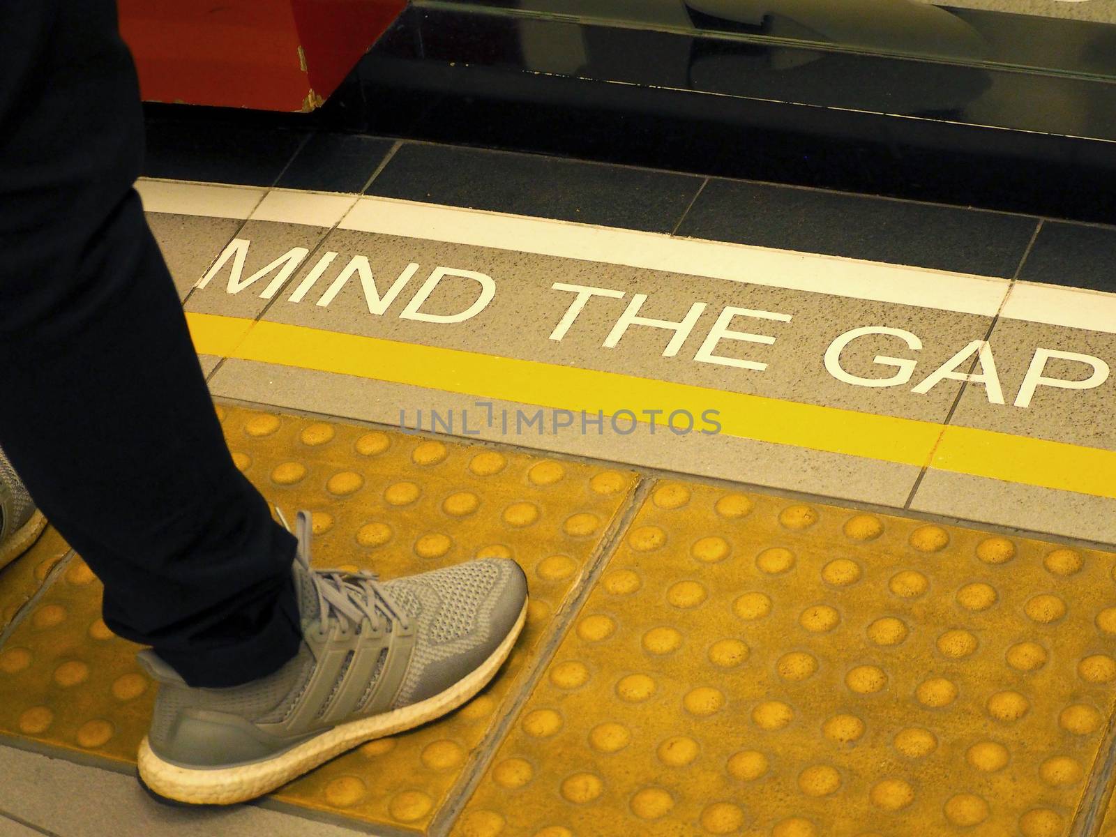 Mind the gap text sign on floor between train and platform station and high angle view.