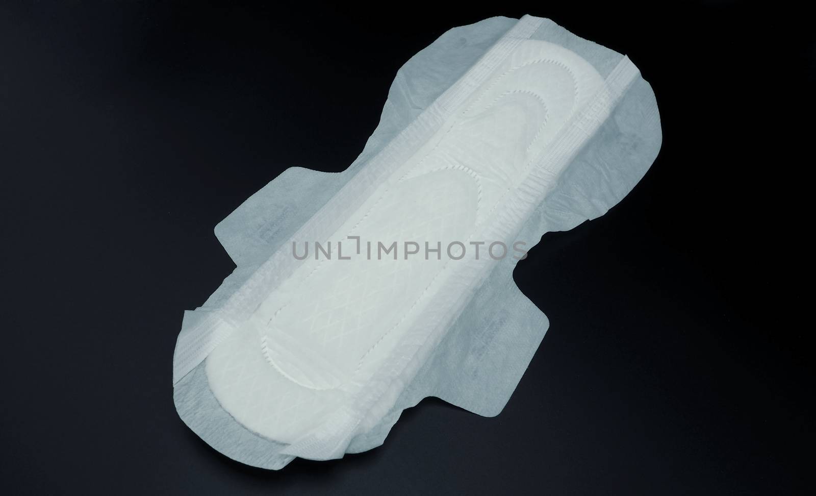 Sanitary napkin white color on black background and very soft and hygiene protection absorbent for woman menstrual at night. 