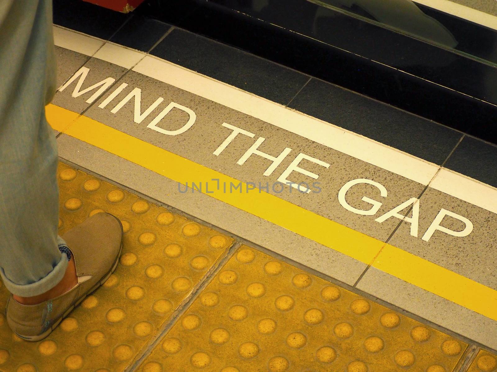 Mind the gap text sign on floor between train and platform station and high angle view.