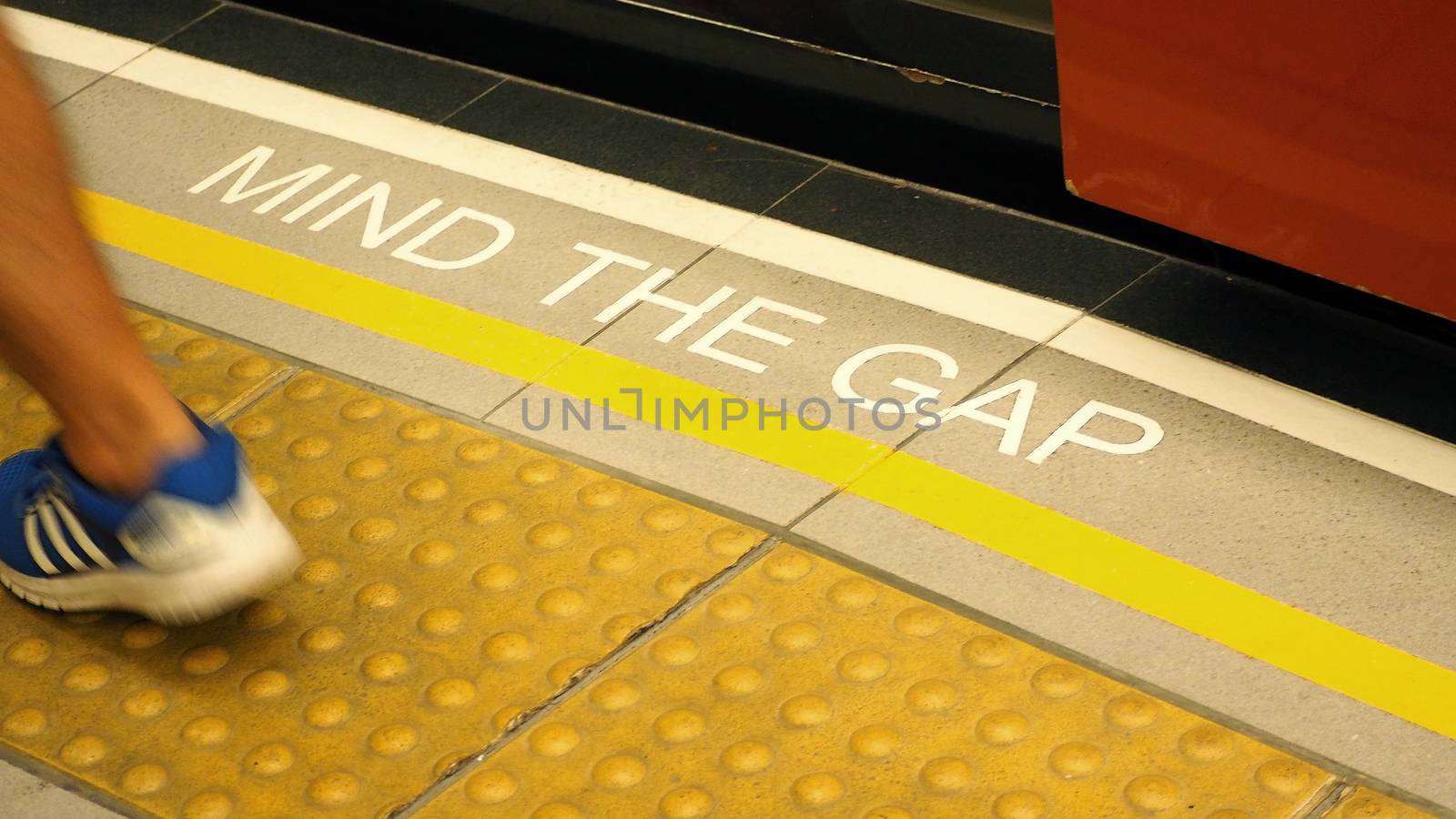 Mind the gap text sign on floor between train and platform station and high angle view.