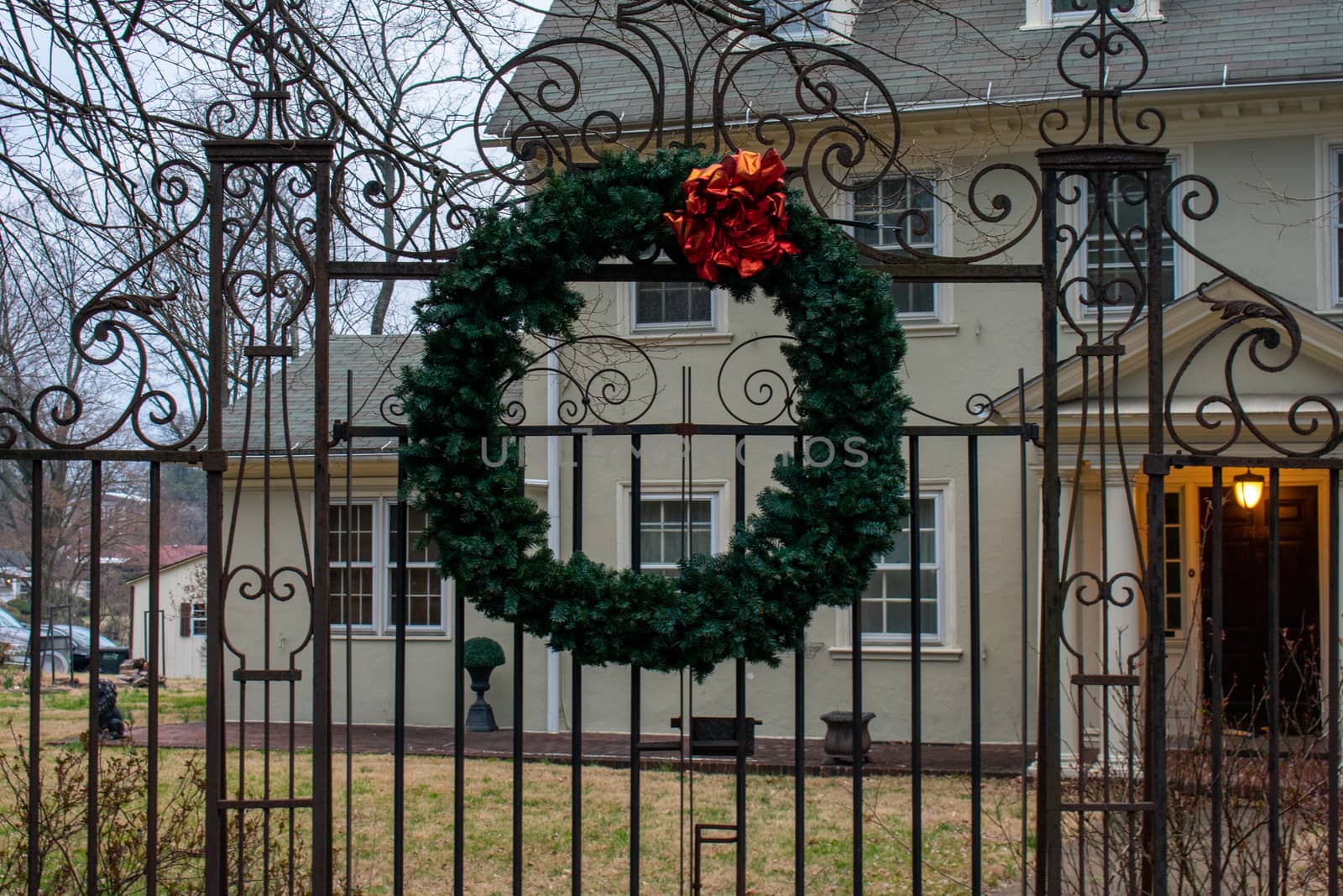 A Christmas Wreath Hanging on an Ornamental Black Fence by bju12290