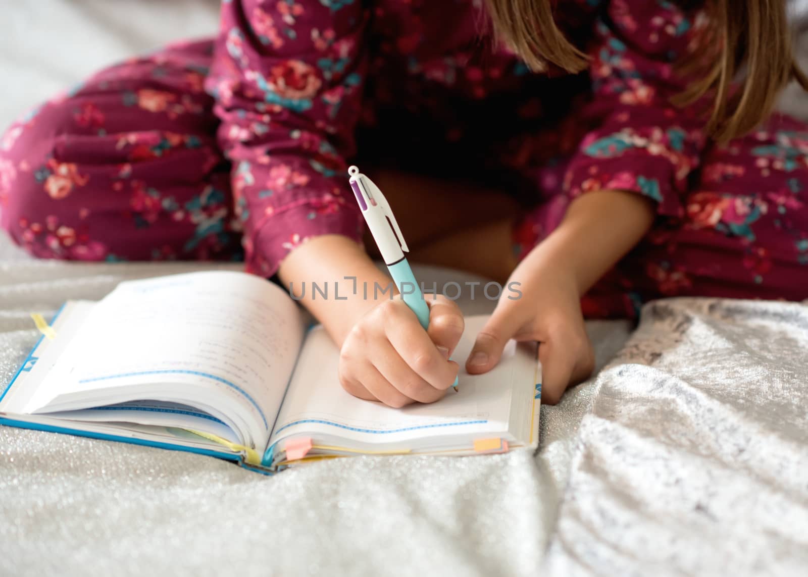 girl sitting on a bed and writing on a notebook