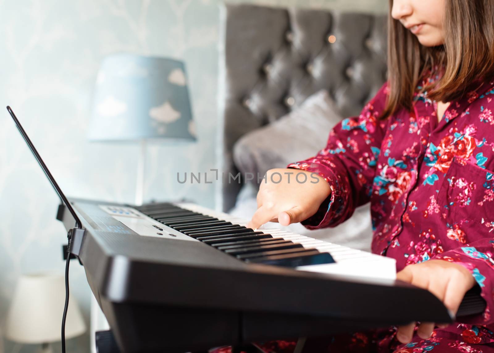 Girl in pajamas playing piano in a room