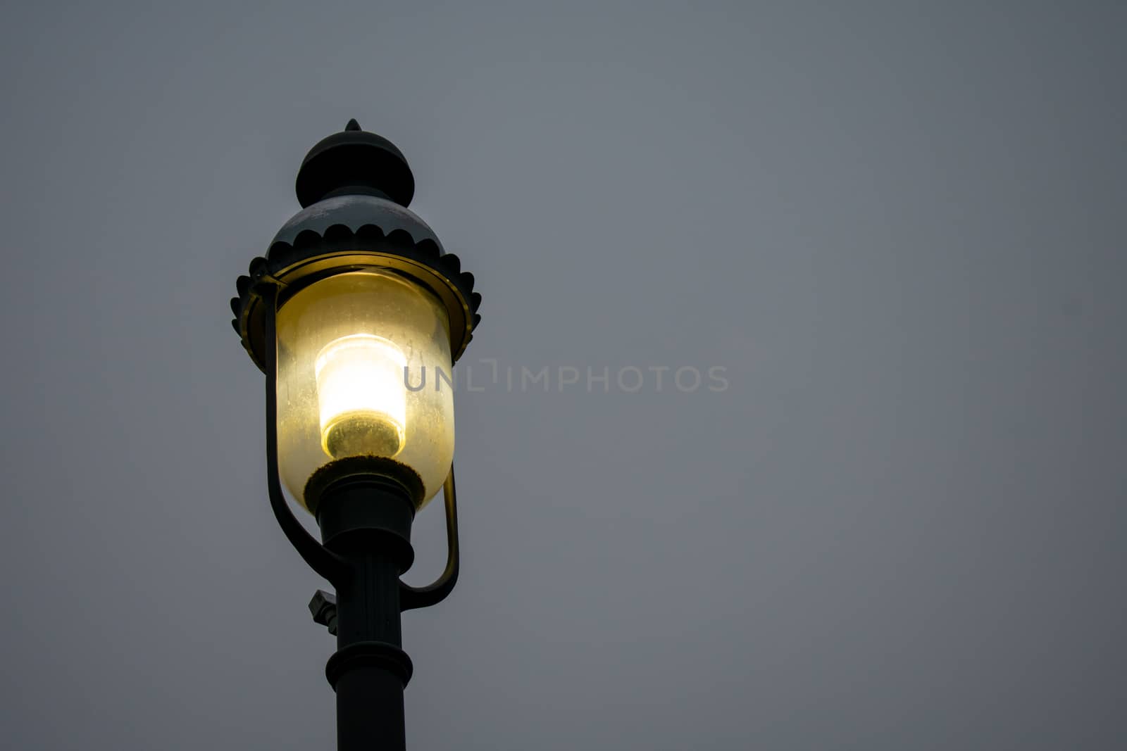 An Old Fashioned Black Metal Street Lamp on a Gray Overcast Sky