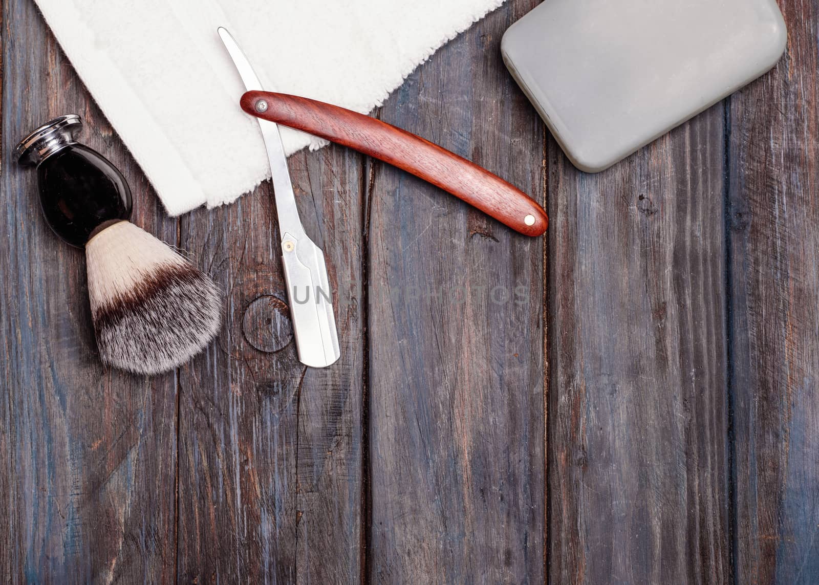 Razor, brush, perfume, towels on a wooden background.