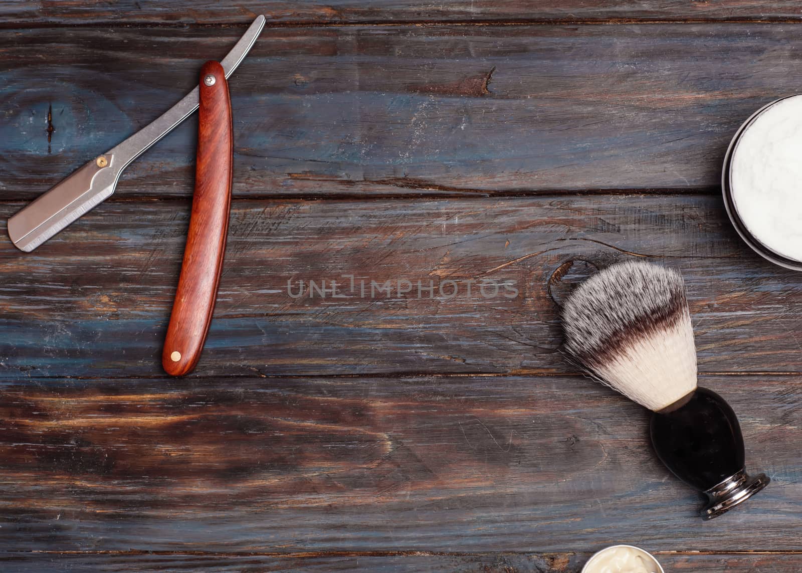 Razor, brush, balsam, perfume on a wooden background.