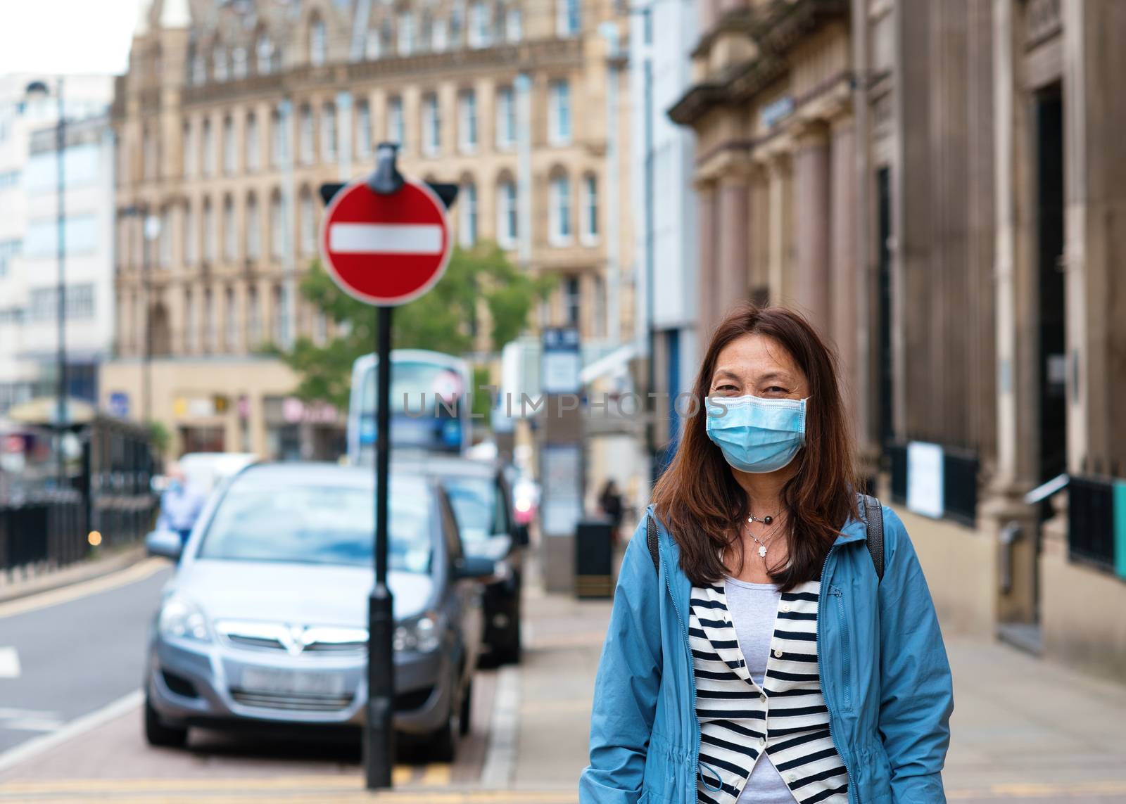 Asian woman wearing a face mask walking around city by Iryna_Melnyk