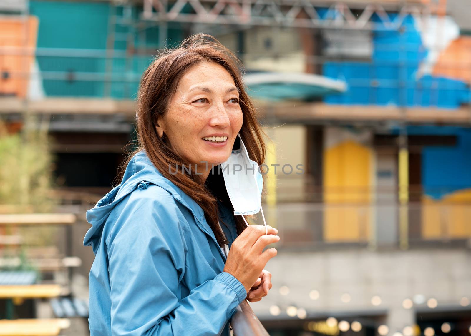 Asian woman wearing a face mask walking around city and smiling by Iryna_Melnyk
