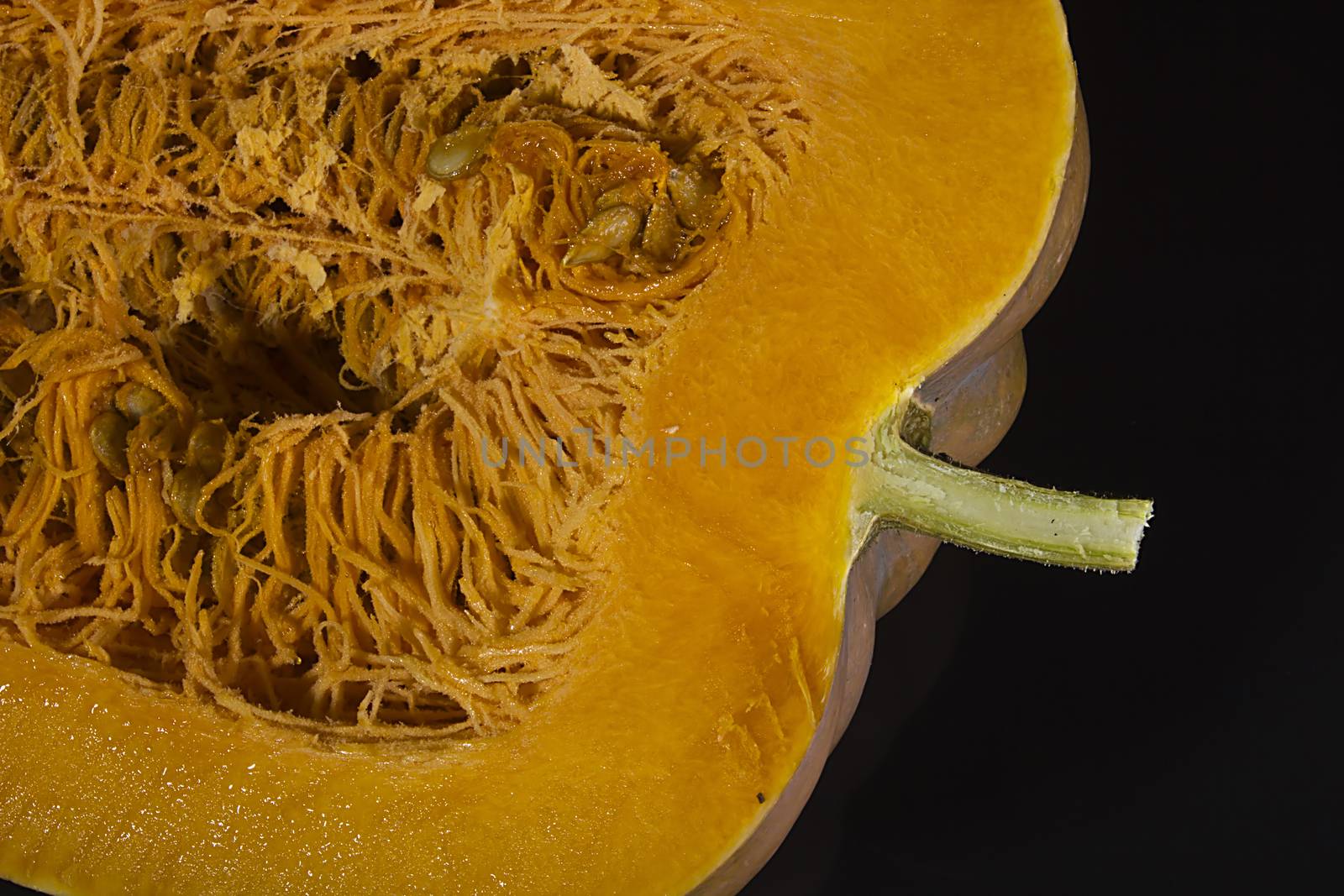 Cut ripe orange pumpkin on black background