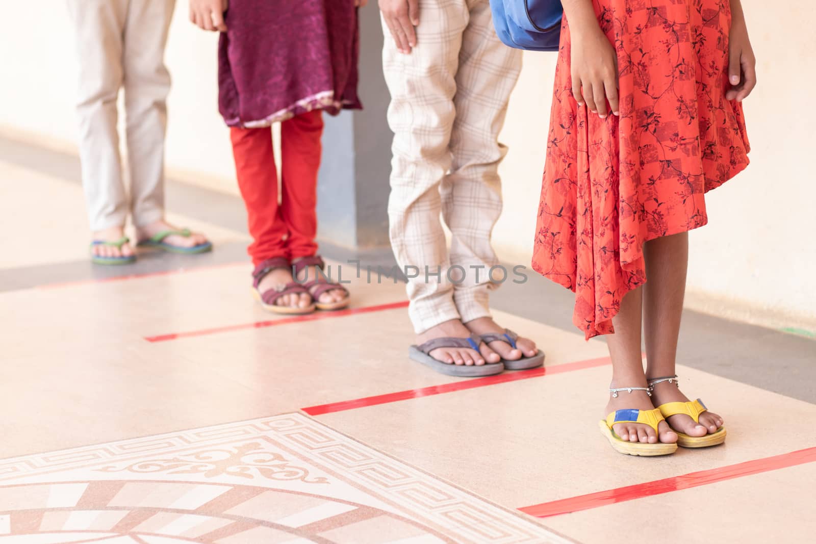 Group of Unrecognized students going inside classroom on social distance marked line in front of class room - concept of coronavirus or covid-19 safety measures at school.