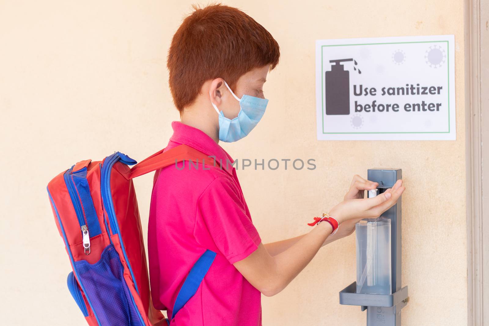 Kid with medical mask using hand sanitizer before entering classroom - concept of back to school or school reopen and coronavirus or covid-19 safety measures.