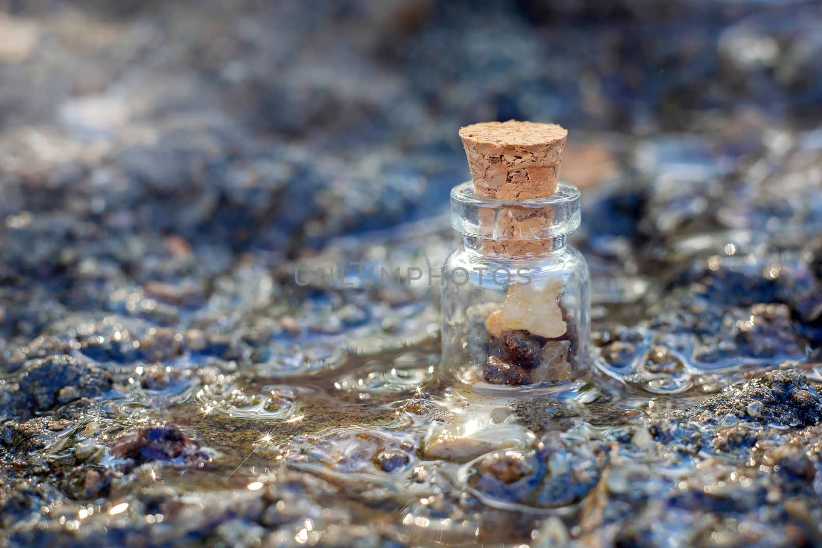 A small decorative jar with stones inside is in the stream. Jar with a cork.