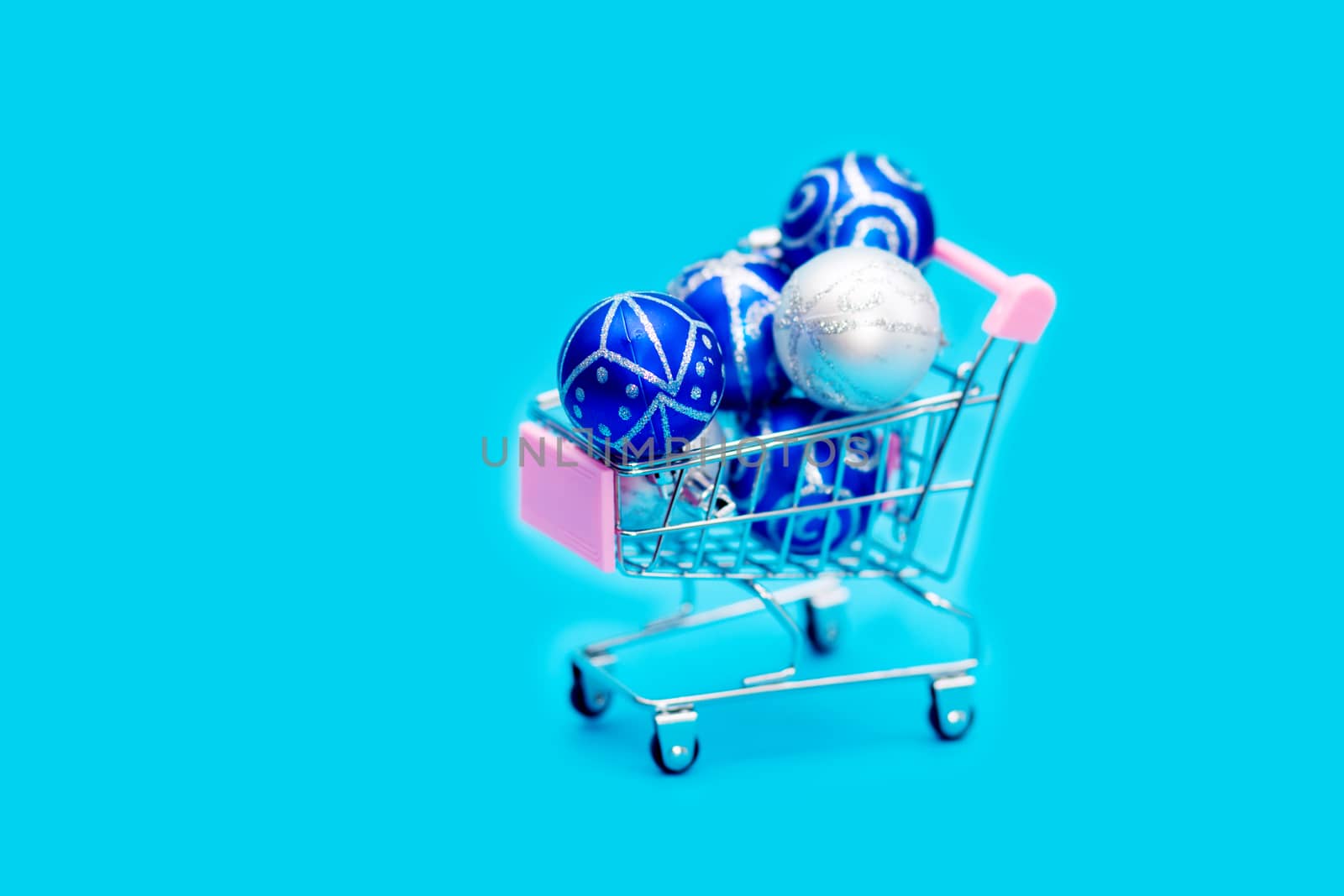 Blue Christmas balls are stacked in a small shopping cart. Christmas preparations