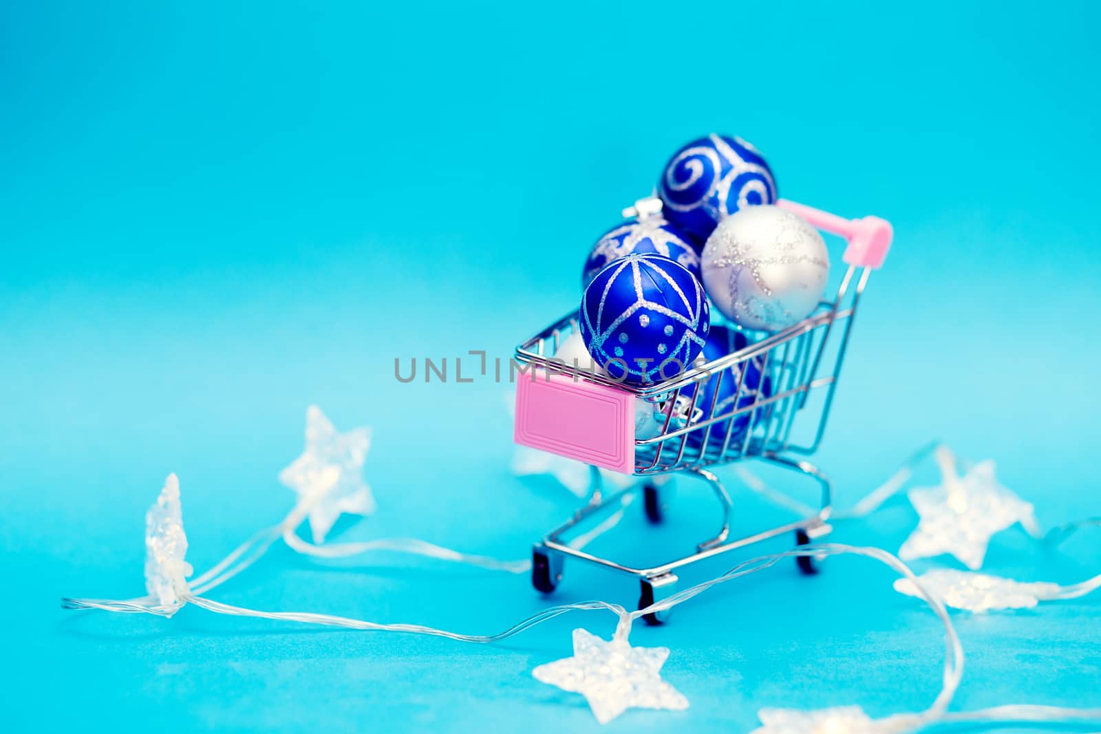 Blue Christmas balls are stacked in a small shopping cart. Christmas preparations