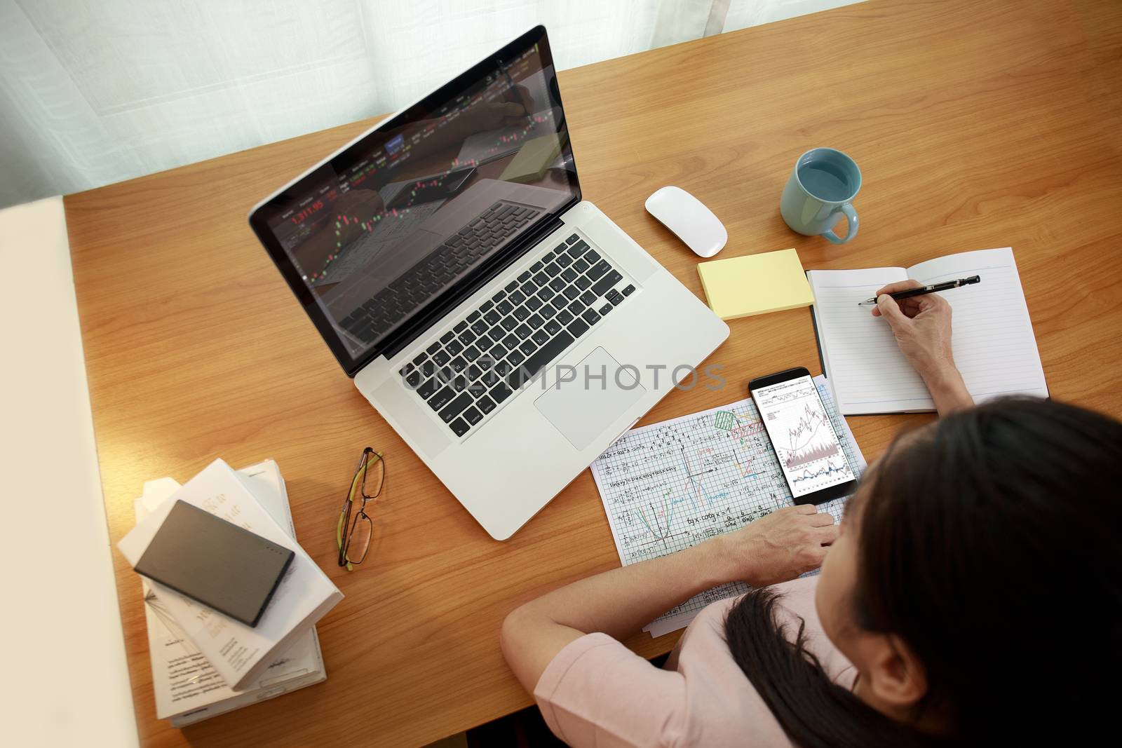 Business women use smart phone and laptop analysis stock market chart. Business people use laptop trade sell and buy stock market at home.