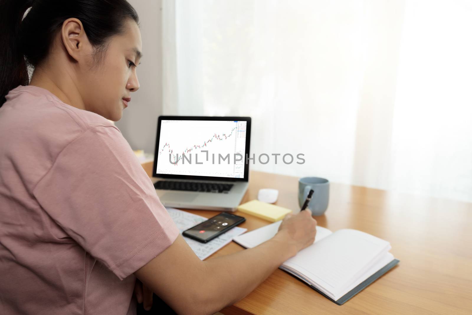 Business women use smart phone and laptop analysis stock market chart. Business people use laptop trade sell and buy stock market at home.