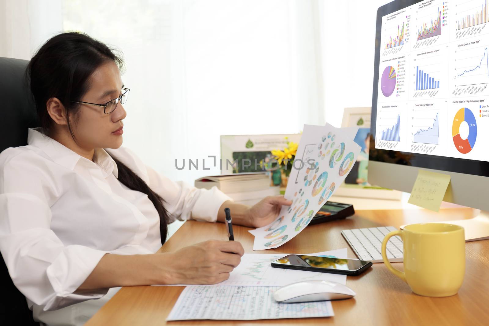 Business woman working in office with computer holding chart report paper and looking. business people working at home with paper and PC screen. Business and finance ,work at home concept