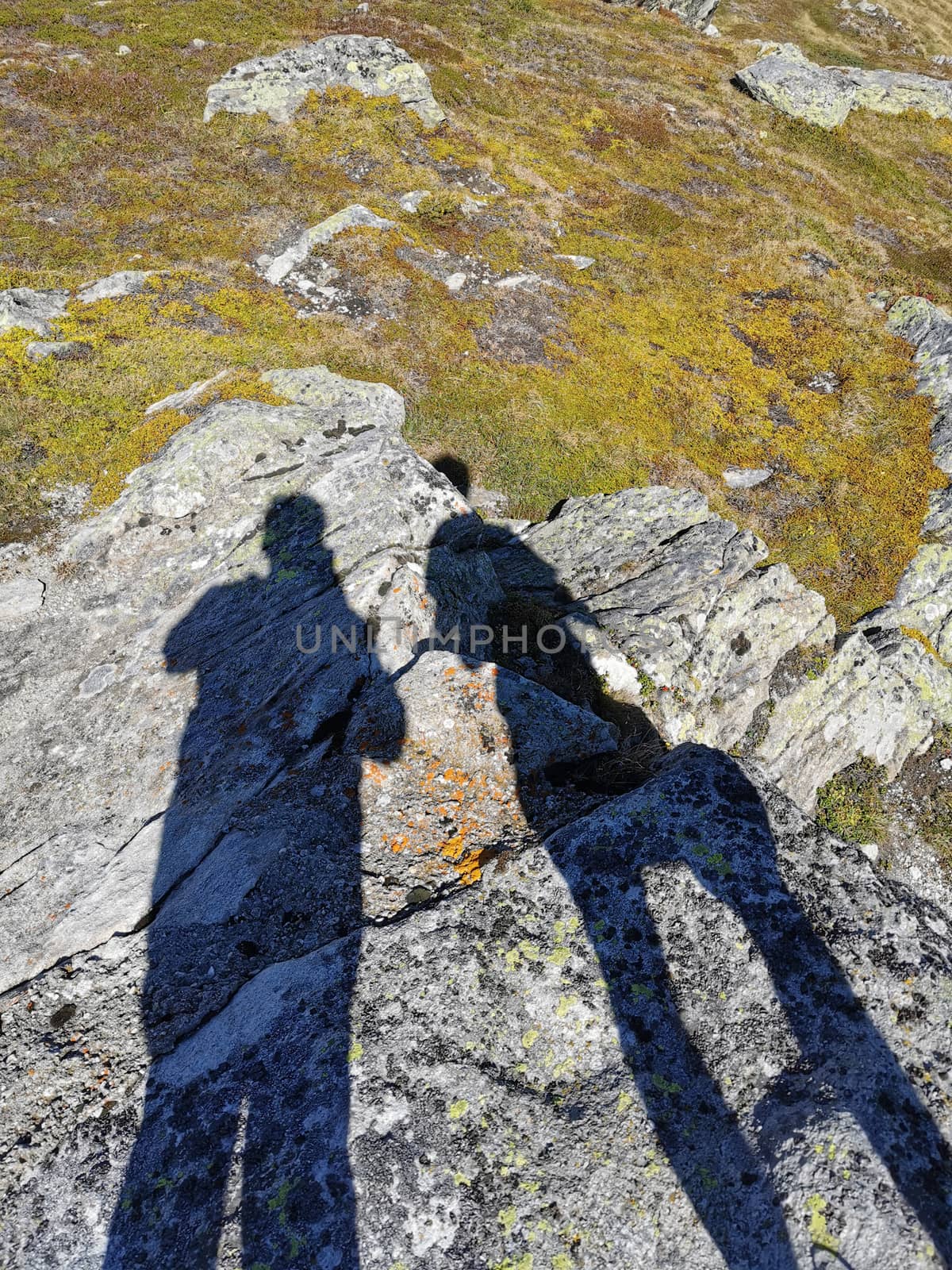 silhouette of tow photographers on rocks in Swiss alps. Copy space by PeterHofstetter