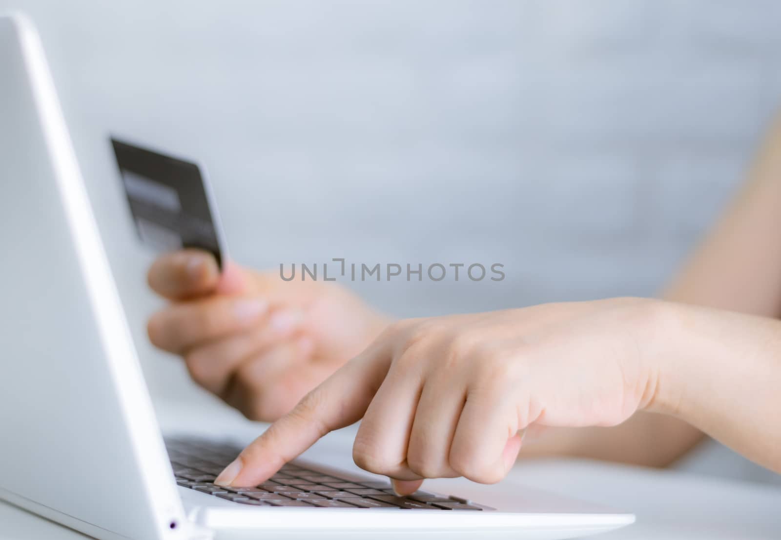 Hands holding credit card on the keyboard online shopping on lap by sompongtom