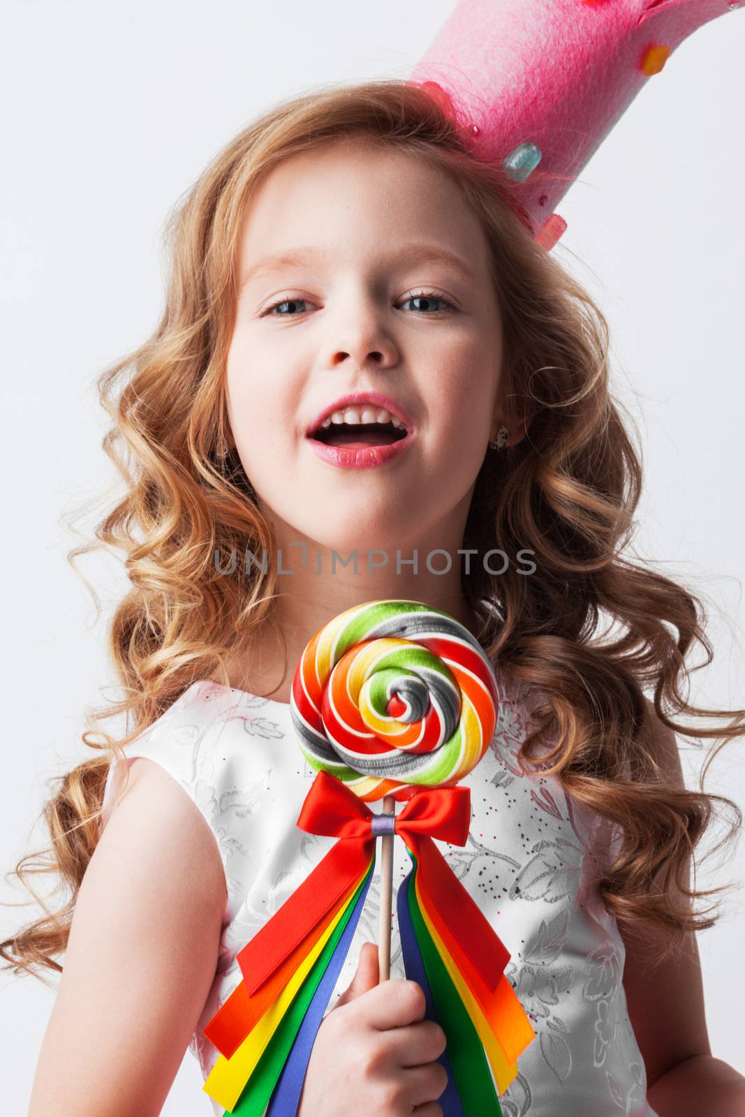 Beautiful excited candy princess girl in crown holding big lollipop