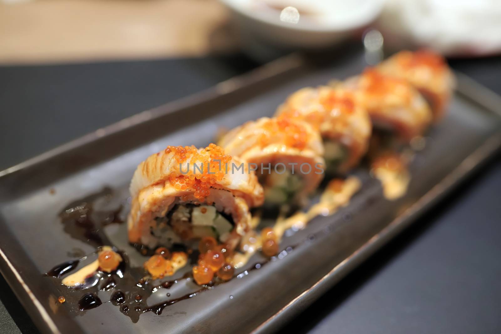 Engawa roll Topped with orange flying fish roe In a square plate In a japanese restaurant. Selective focus.